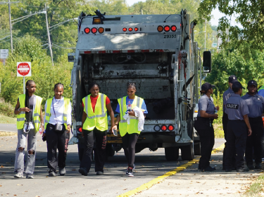  students walking in front of garbage truck